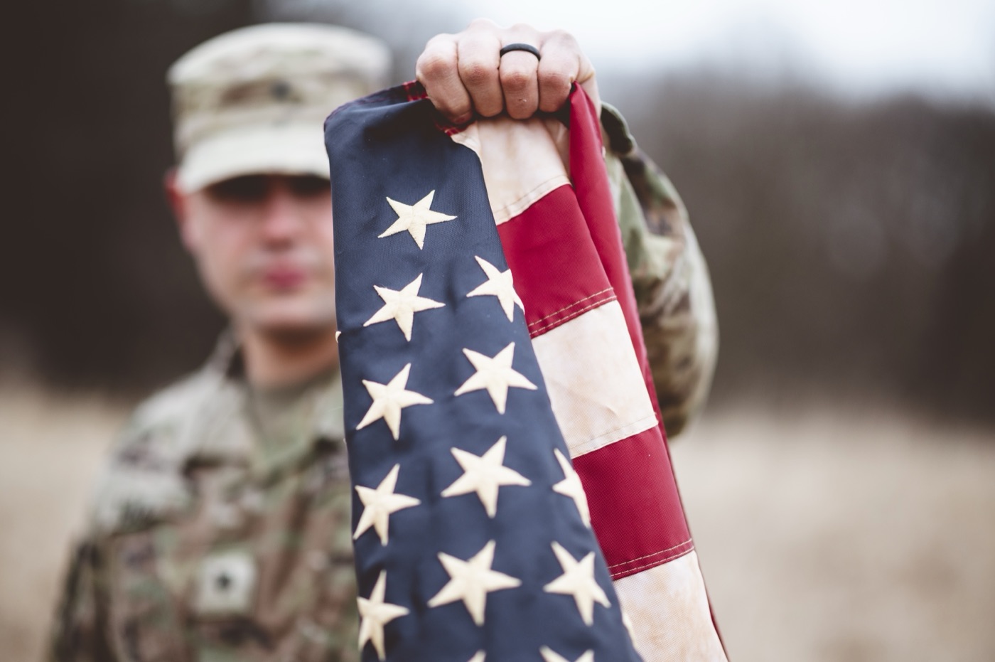 A person in uniform holding the United States flag